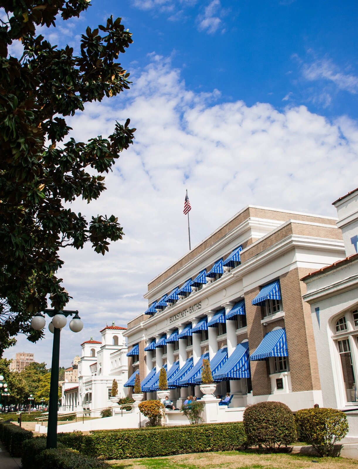The brick and white-columned Buckstaff Baths building on Bathhouse Row in Hot Springs, with blue and white striped awnings over every window