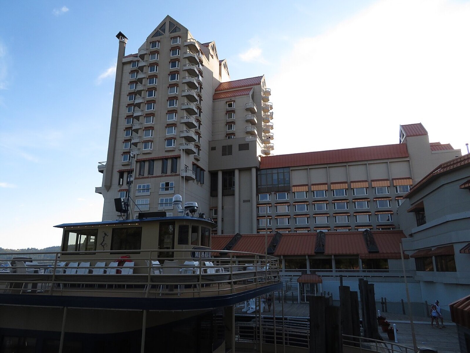The tall hotel tower and lower wings of the Coeur d'Alene Resort beside the lake, with a moored boat in the foreground