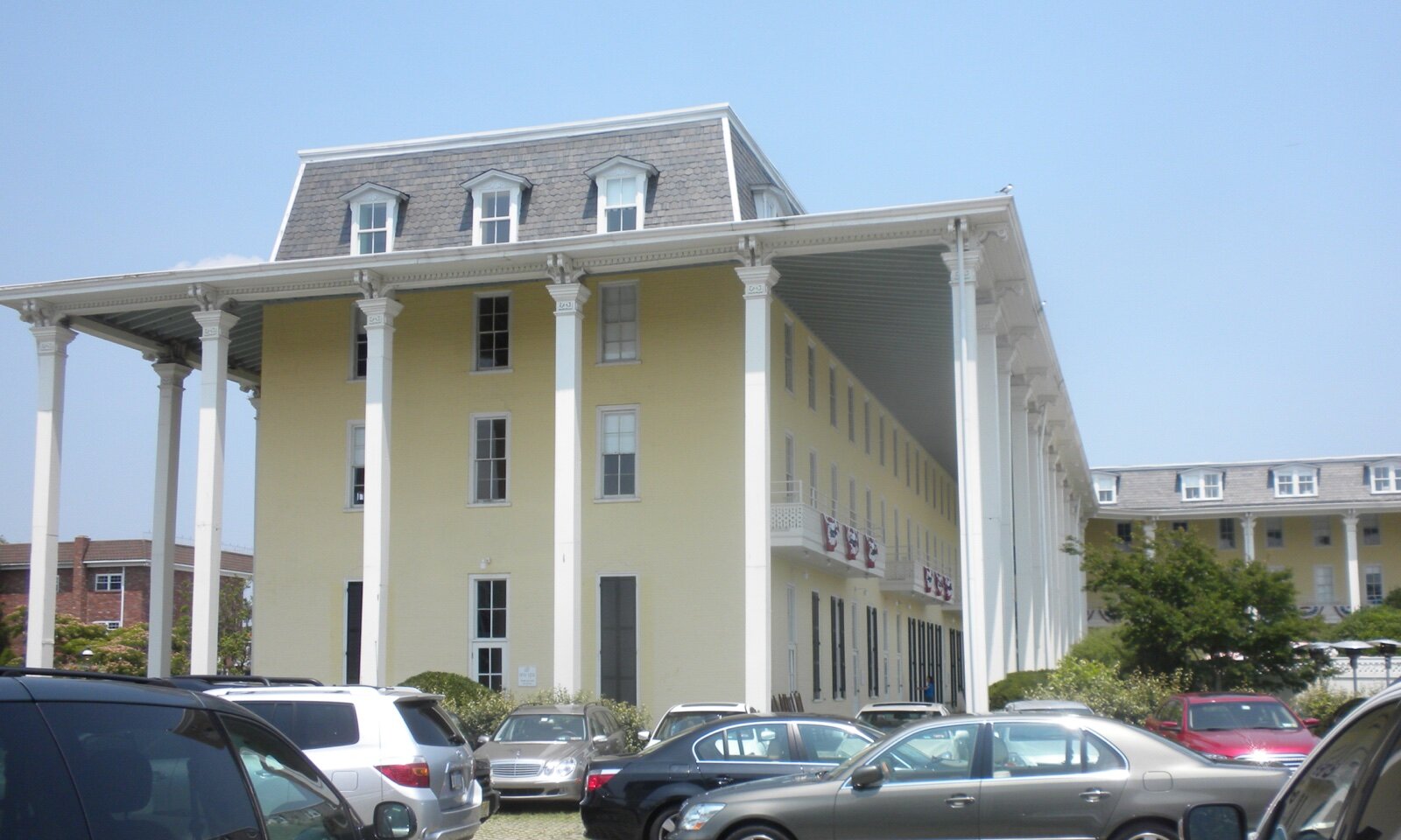 The pale yellow Congress Hall hotel in Cape May, New Jersey, with a tall white colonnade running along its side under a clear blue sky