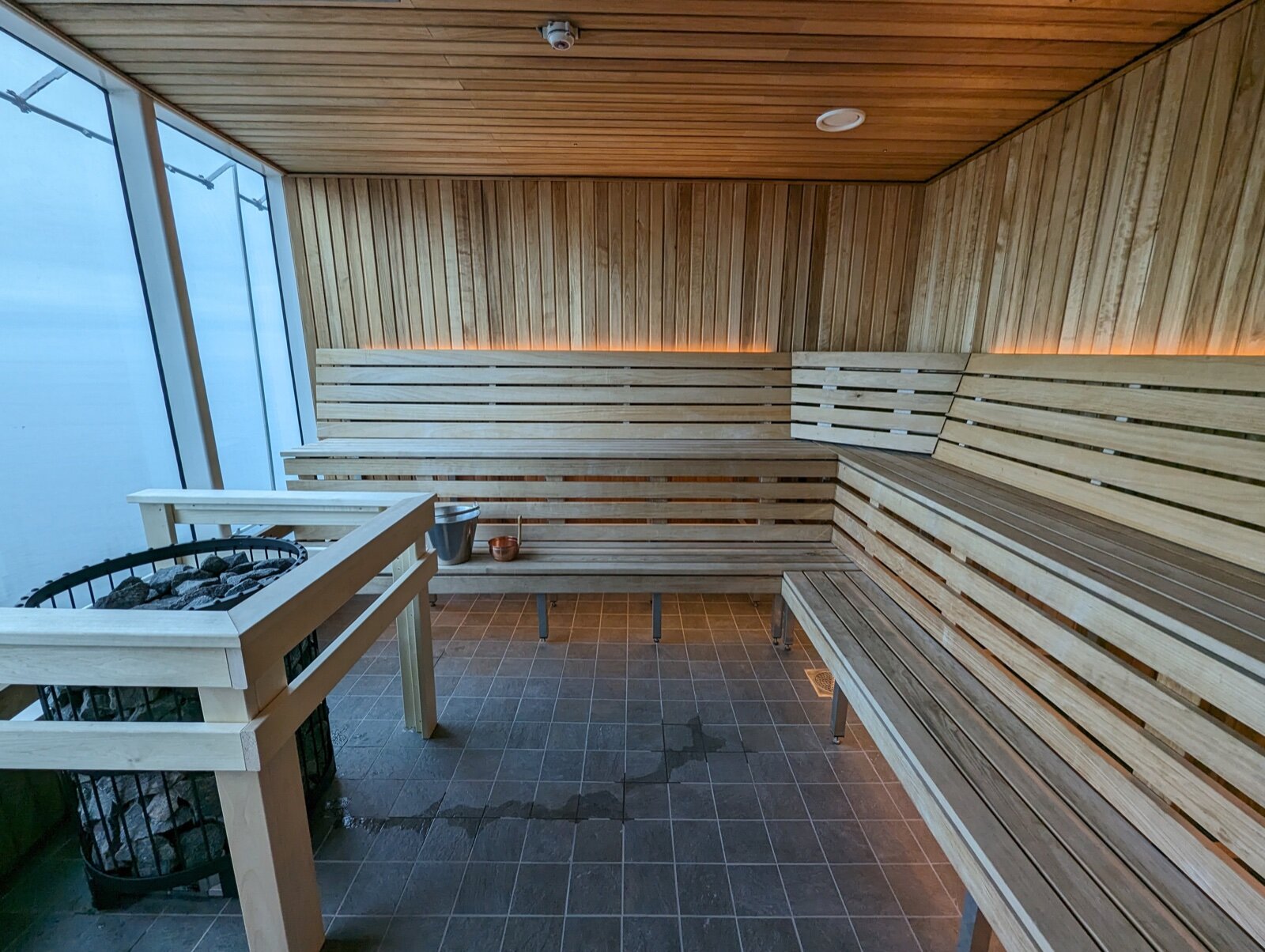 A modern wood-lined sauna interior with tiered benches and warm lighting