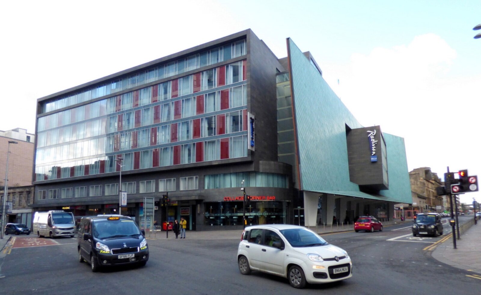 The Radisson Blu hotel in Glasgow city centre, a glass block beside a green copper-clad wing, with taxis and cars on the road in front