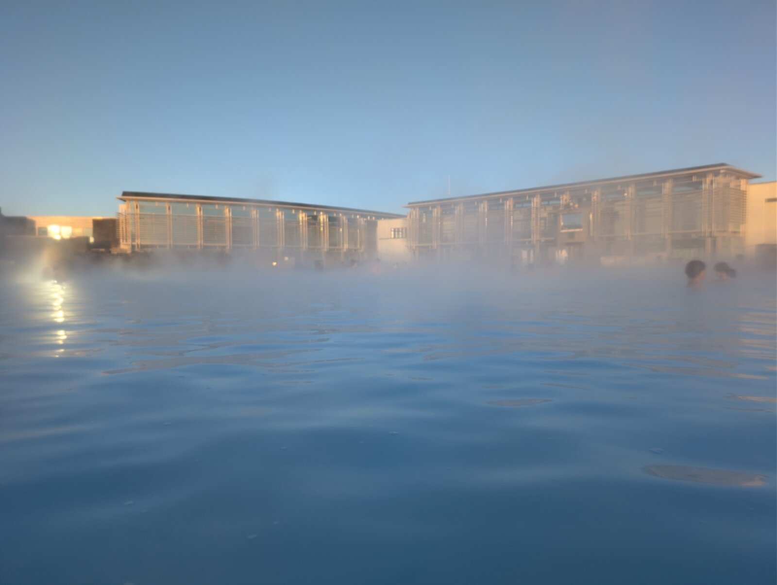 Steam rising off the Blue Lagoon bathing pool in Iceland with the spa buildings behind